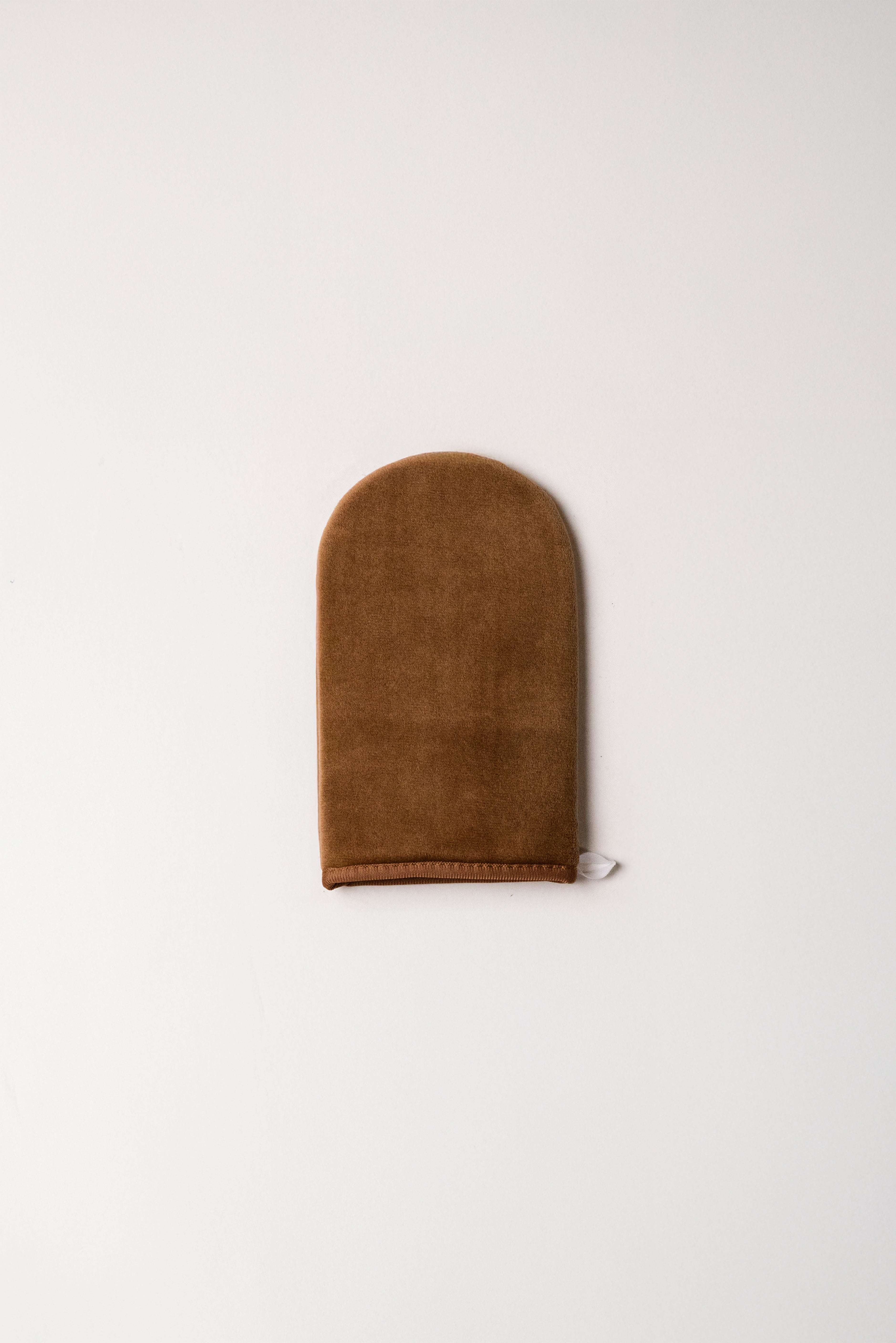 Brown suede tanning mitt on a white background
